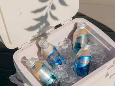 A white cooler open with ice and multiple Surfwave cans inside for drinks.