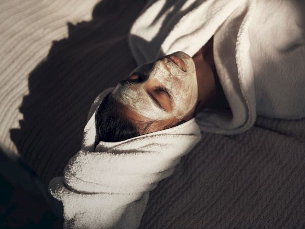 A woman rests asleep, wrapped in a blanket, with warm sunlight highlighting her face.
